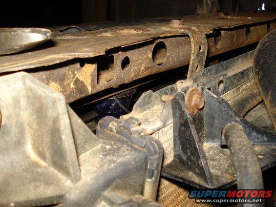 Close-up of rusty metal bracket attached to a vehicle's radiator support