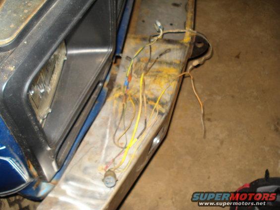 Close-up of exposed wiring on a vehicle's front end, near the headlight