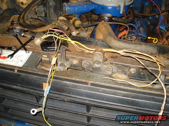 Engine bay wiring with blue engine block and radiator hoses. Wires are yellow, pink, and white