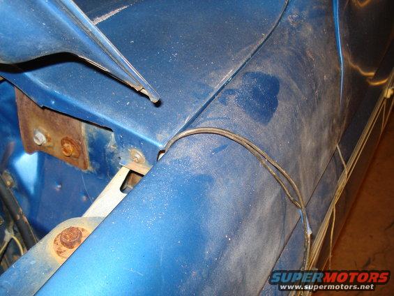 Blue fender with visible wiring and rust on mounting bracket. 1985 Ford F-150