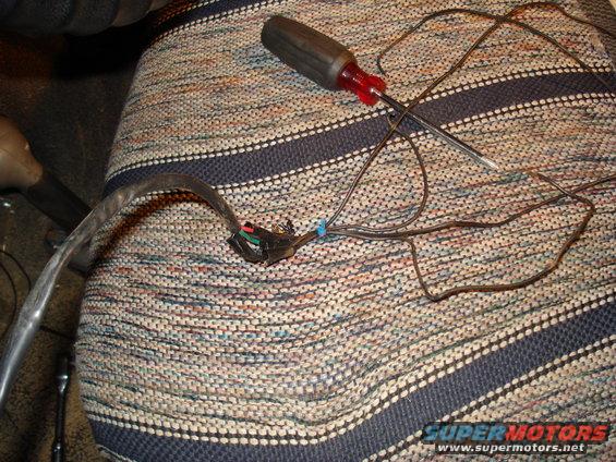 Wiring harness with exposed wires and a screwdriver on a striped fabric seat