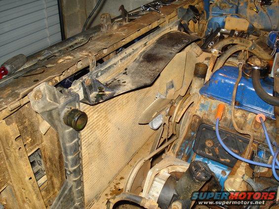 Engine bay showing radiator, fan, and blue valve covers. Some parts are rusty