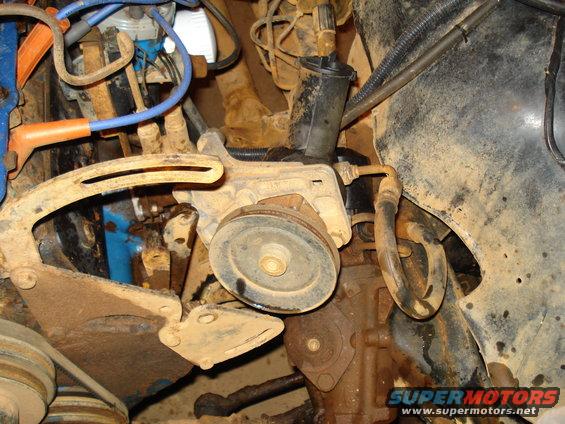 Close-up of engine components including pulleys, hoses, and wiring