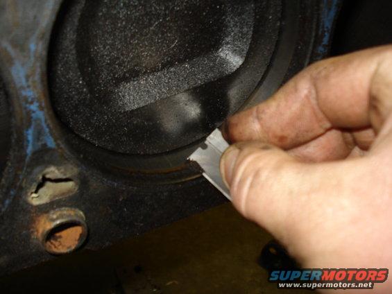 Engine cylinder with a hand holding a metal scraper inside
