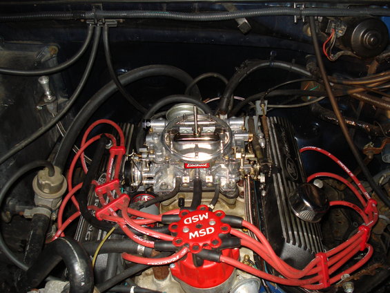 Close-up of an engine bay showing a carburetor and red MSD spark plug wires