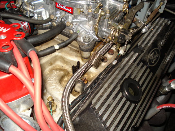 Close-up of a Ford engine's valve cover and Edelbrock carburetor with red spark plug wires