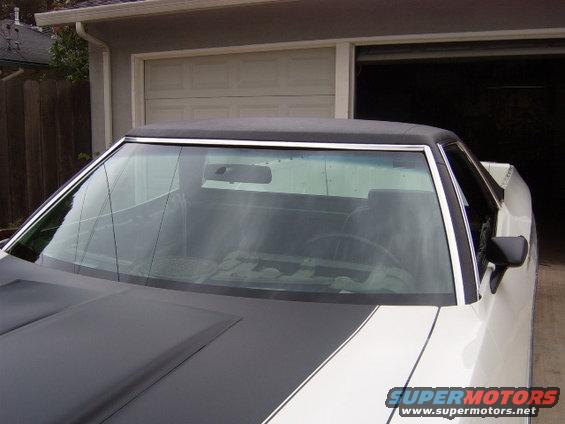 White 1972 Ford Ranchero with black hood stripes, parked in front of a garage