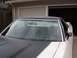 1973 Ford Ranchero - A white 1972 Ford Ranchero with black racing stripes on the hood is parked in front of a garage door.