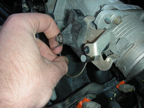 Hand installing throttle cable on engine part