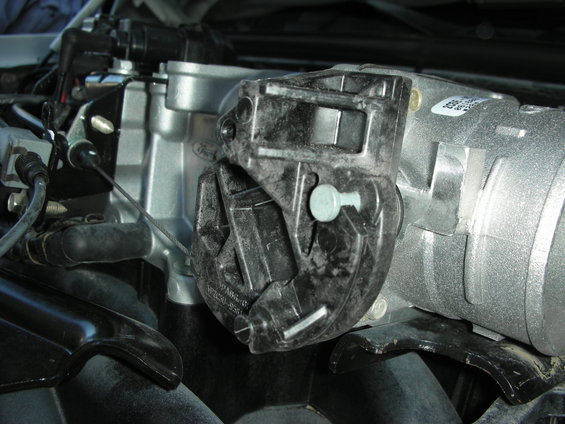 Close-up of engine intake manifold and throttle body assembly with visible part numbers