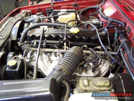 Engine bay of a Jeep, showing the engine block, air intake, and various hoses and wires