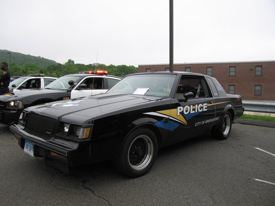 Black police car with 'POLICE' and 'CITY OF BRIDGEPORT' on the side, parked next to other police cars