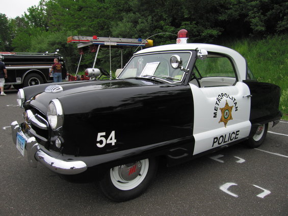 Black and white Nash Metropolitan police car with number 54 on the fender