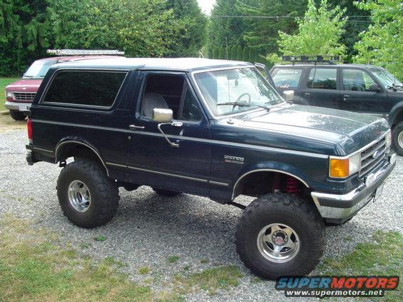 Dark blue lifted 1990 Ford Bronco with aftermarket wheels and tires