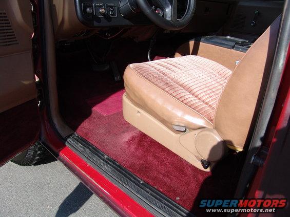 Red 1991 Ford Bronco interior with tan cloth seats, red carpet, and dashboard visible