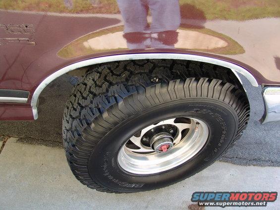 Close-up of a maroon Ford Bronco's front fender and tire. The tire is BFGoodrich All-Terrain T/A