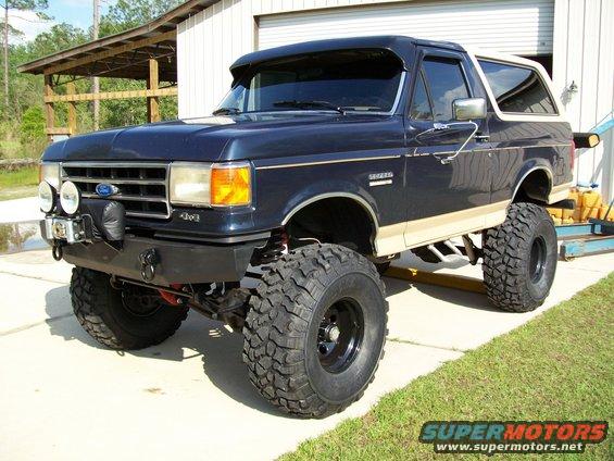 Lifted dark blue 1990 Ford Bronco with tan trim and large off-road tires