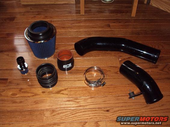 Blue cone air filter, black intake tubes, and hose clamps on a wooden floor