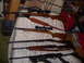 1966 Matchless G80 - A collection of rifles and shotguns are displayed on a bedspread, with scopes visible on some.