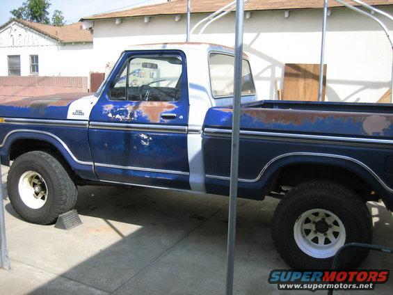 Side view of a blue and white 1979 Ford F-150 pickup truck with rust