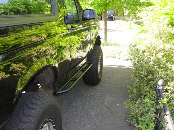 Black SUV with aftermarket side steps and large tires, parked on asphalt