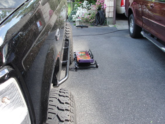 Black SUV side step and aggressive tire, with a purple jack in the foreground