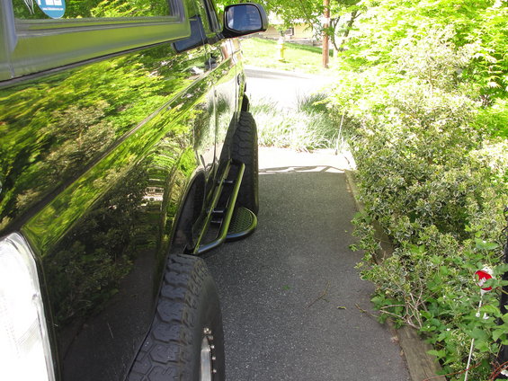 Side view of a black 1995 Ford Bronco with aftermarket steps and off-road tires