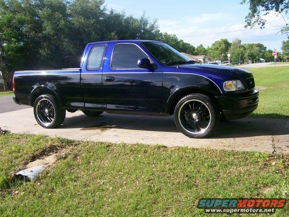 Black and blue 1997 Ford F-150 pickup truck with custom wheels, seen from the side