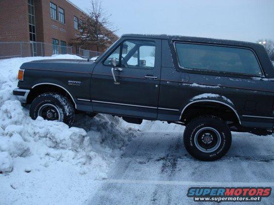 Dark gray 1988 Ford Bronco driving through a snowbank