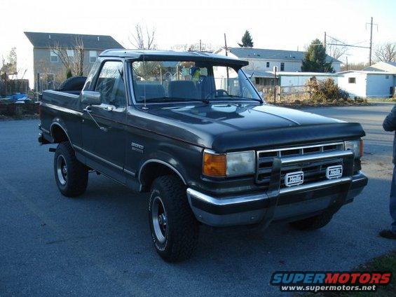 Dark gray Ford Bronco with a black bug deflector and chrome grille guard, parked on asphalt