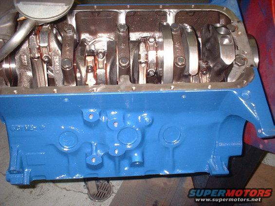 Blue painted engine block with crankshaft and connecting rods visible inside. Watermark "SUPERMOTORS.NET" at bottom right