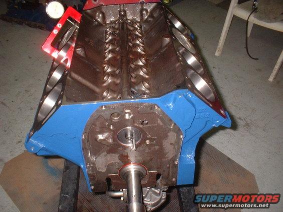 Engine block on stand with a dial indicator measuring tool attached to a red bracket