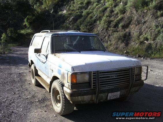 1989 Ford Bronco, 3q-front view, dusty white and blue exterior, on a dirt road