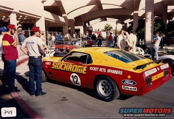 Red and yellow 1970s racing car with "SIDCHROME" livery, number 12, and "Ford" and "Shell" decals