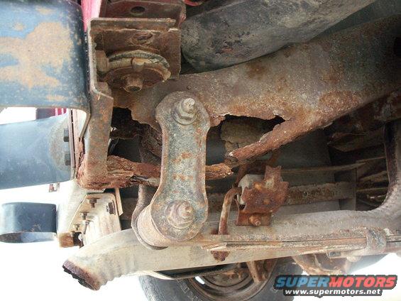 Heavily rusted frame and suspension parts of a vehicle, showing significant corrosion and damage