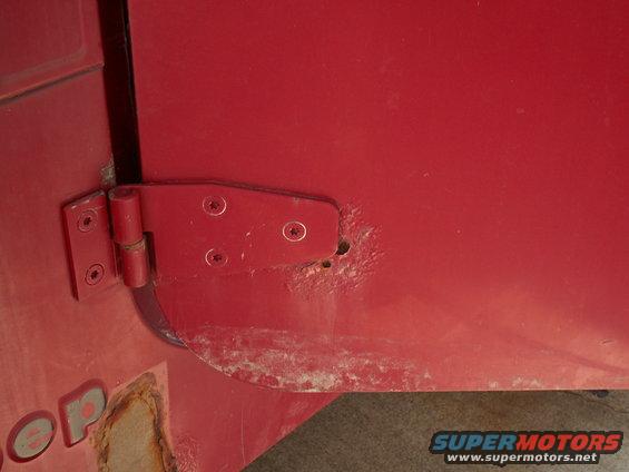 Red Jeep YJ door hinge with rust and visible text 'OP'