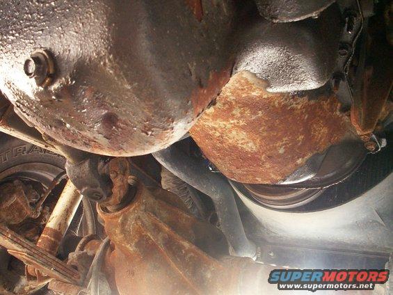 Underside view of rusty vehicle parts, including suspension and drivetrain components