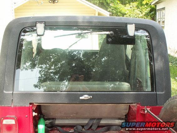Rear of a red Jeep CJ-7 with the hardtop on, showing the rear window and spare tire mount
