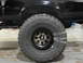 1995 Ford Bronco - Close-up of a black SUV's tire and wheel, wrapped in plastic for protection.