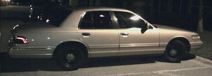 Silver Mercury Grand Marquis parked at night. The car has black wheels and tinted windows