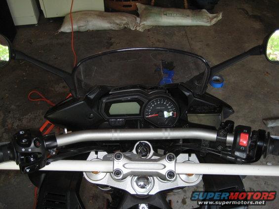 Motorcycle handlebars, digital display, and analog tachometer. Supermotors.net logo visible