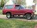 1994 Ford Bronco - Side view of a red 1994 Ford Bronco with visible rust damage.