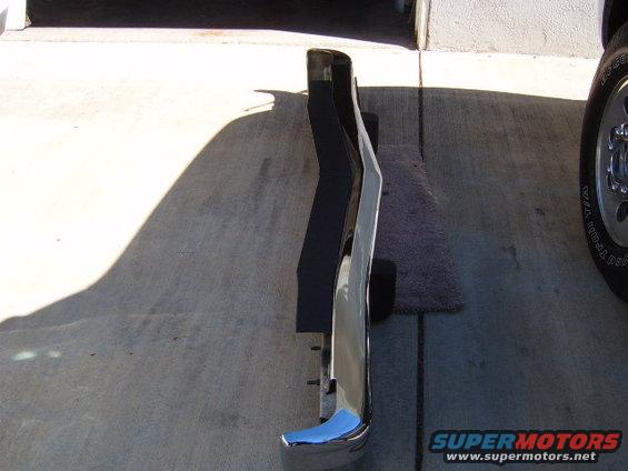 Chrome bumper with black rubber strip, angled view on concrete