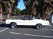 1973 Ford Ranchero - A white coupe utility with a black hood and roof is parked in a lot with palm trees overhead.
