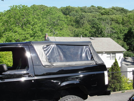 Black soft top SUV, side view, showing clear plastic rear window and chrome trim
