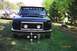 1994 Ford F-150 - A black Ford truck is parked on grass with trophies displayed in front, while another vehicle sits with its hood open in the background.