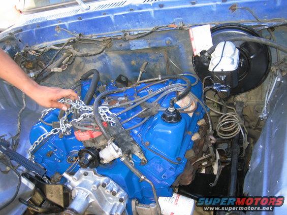 Blue engine in bay with chains being handled by a person's hand