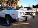 1973 Ford Ranchero - A white 1977 Ford Ranchero is parked outdoors, with palm trees and buildings in the background.