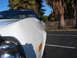 1973 Ford Ranchero - A white car is parked outside with palm trees and a wooden fence in the background.