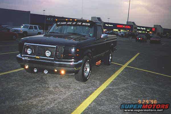 Black 1994 Ford F-150 pickup truck parked in a lot at dusk, with 'THE DARK SIDE OF THE MOON' text on the visor